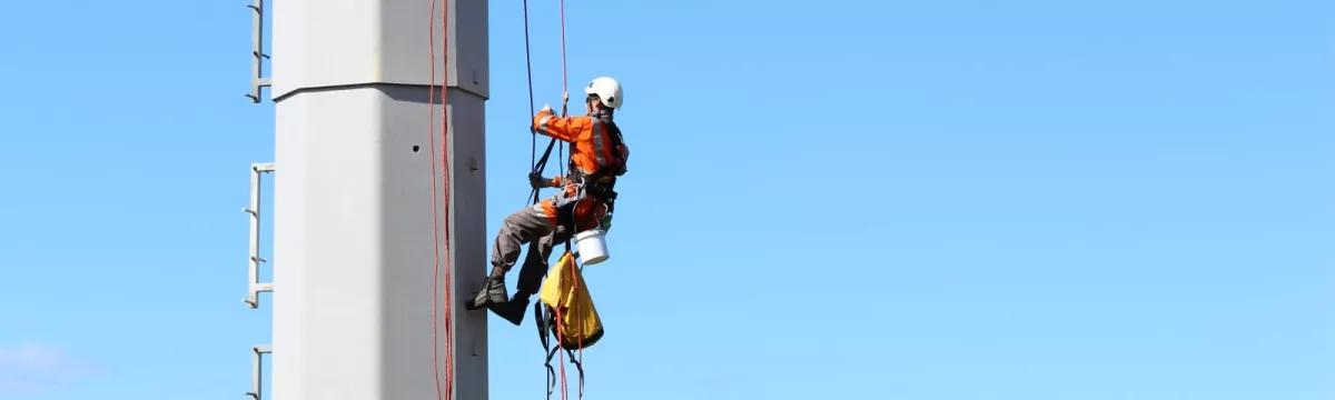 An Avalon team member on a rope inspecting a wind turbine pylon